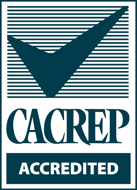 The words on this certification mark are "CACREP ACCREDITED," incorporated into a design featuring a stylized dark checkmark against a dark horizontally lined background. In the color version of the mark, the checkmark, the horizontal lines and the word CACREP are dark blue against a white background.