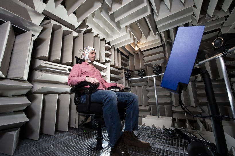 Participant seated in anechoic chamber wearing an EEG cap