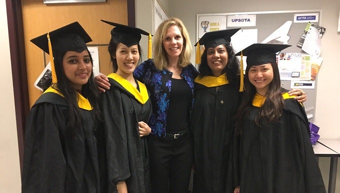 OT faculty member with students in caps and gowns