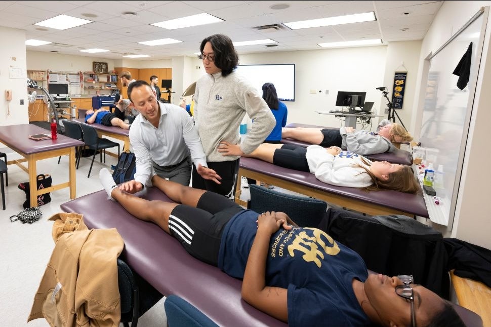 sports medicine guest instructor demonstrates technique for male student on female student
