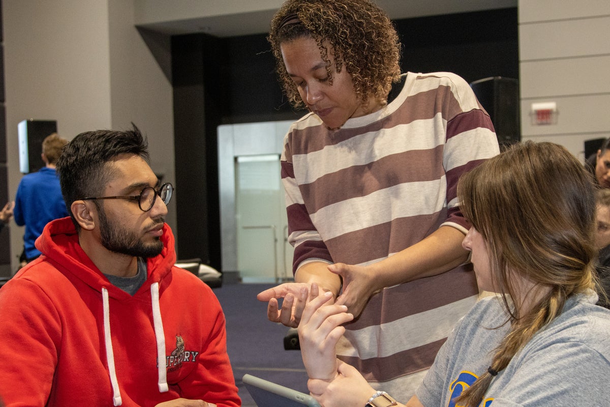 Assistant Professor Reivian Berrios-Barillas (center) demonstrates an examination of the forearm for possible impairment