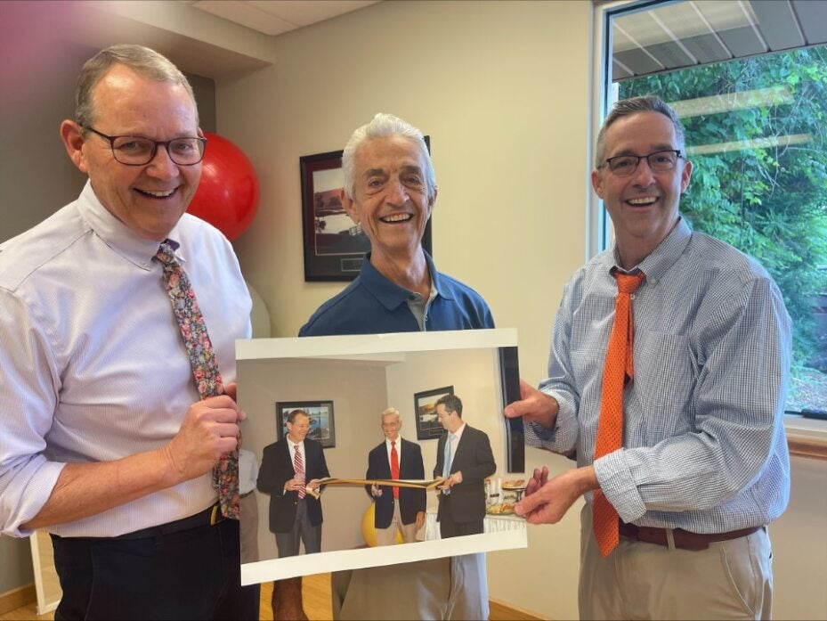 Bruce Rosborough, Keith Erb and Kenny Erb in July 2023 holding the picture from 2011 at the ribbon cutting of their new office building