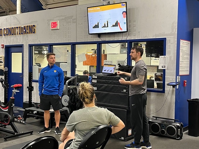 Proessl and Aaron Duvall demonstrating Pitt Athletics sports science equipment 