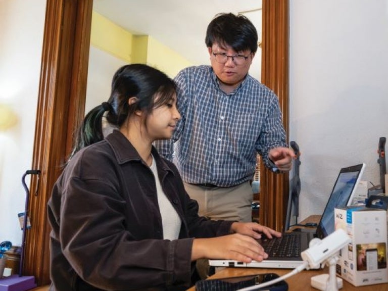 Health Informatics Assistant Professor Yong Choi, standing, discusses smart home technology with student researcher, Sukritta Suksawang, at the Healthy Home Lab. 