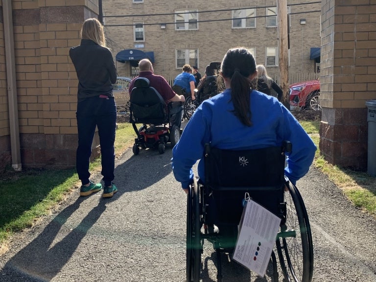 Students and instructors testing wheelchair function outdoors.