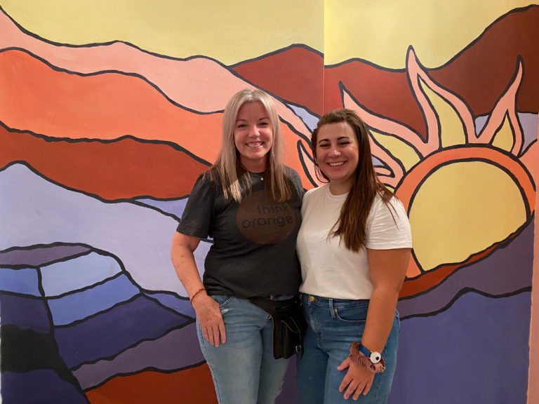 Sarah Newborn (right) and her supervisor in front of mural at the arts center