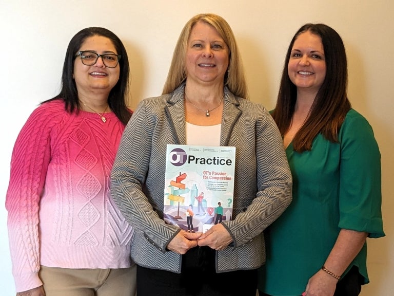 Three OT faculty holding issue of OT Practice magazine