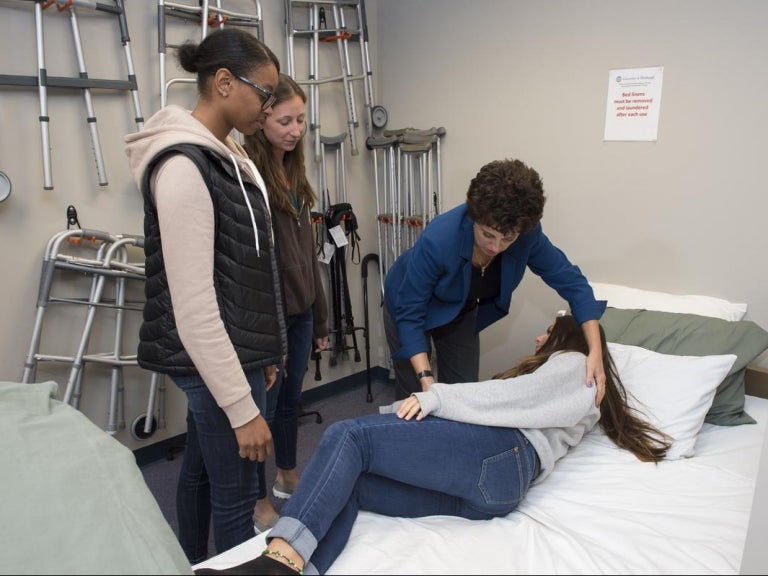 Joanne Baird shows OT students how to place a patient in bed