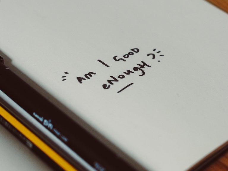 notebook page with "am I good enough" in text