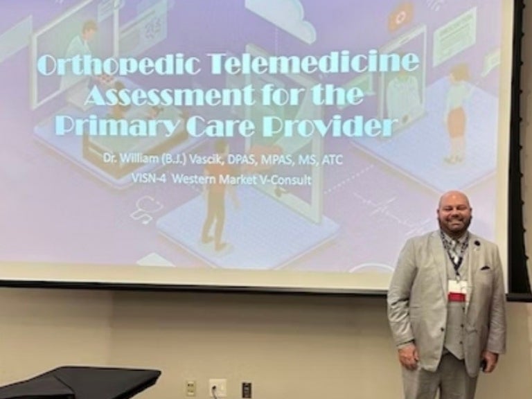 B.J. Vascik standing in front of a screen with an "Orthopedic Telemedicine Assessment for the Primary Care Provider" presentation.