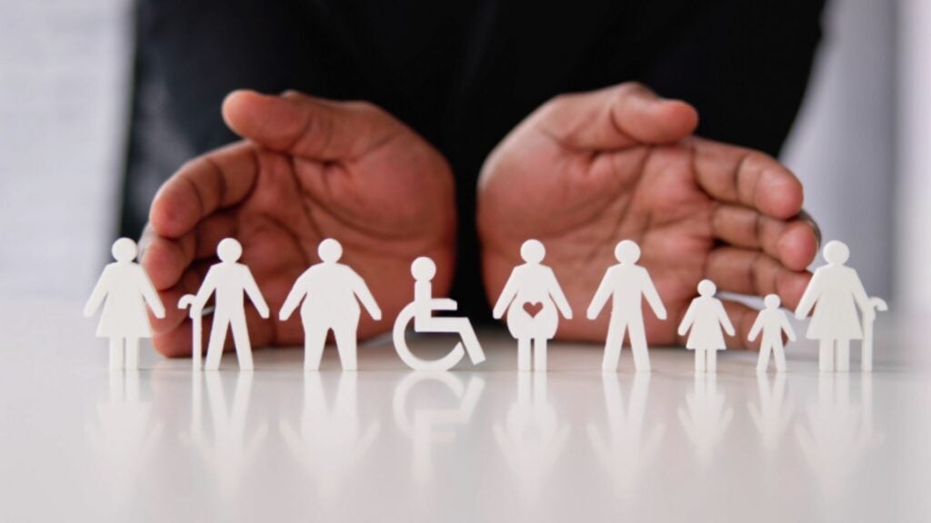 Hands serve as a backdrop for cut outs of people with a variety of disabilities and sizes.