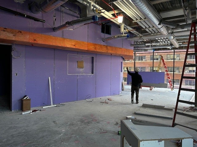 Construction site of the new building for SHRS featuring a purple drywalled section of the Student Social Space.