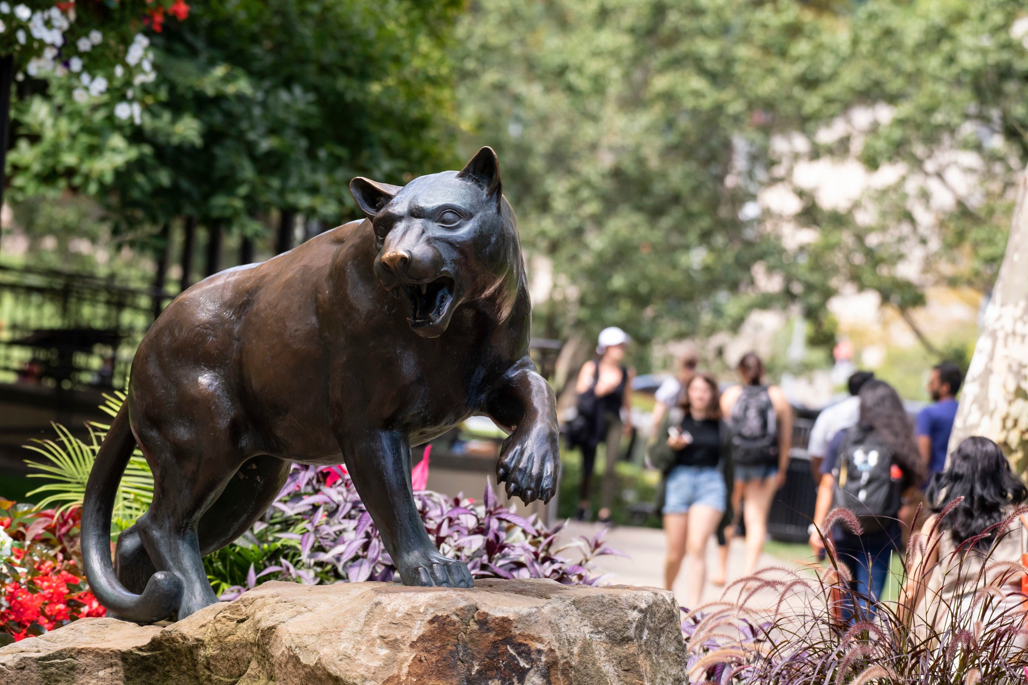 Panther statue on campus with students in the background.
