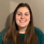 Woman with long brown hair wearing a dark green sweater.