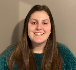 Woman with long brown hair wearing a dark green sweater.