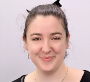 A woman with brown hair pulled back in a black bow wearing a black shirt.