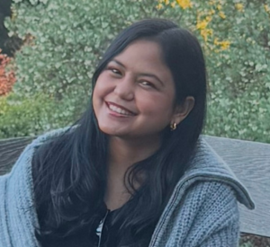 Woman with long dark hair wearing a gray sweater over a black shirt.