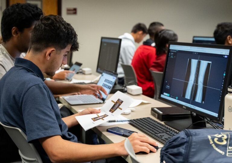 Male student working on a desktop computer with an image of an x-ray image of legs