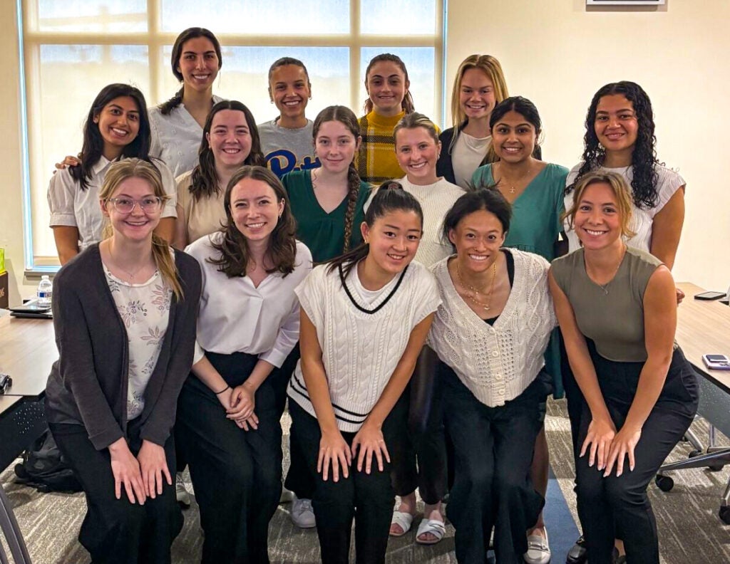 A group of 15 women pose and smile at the camera