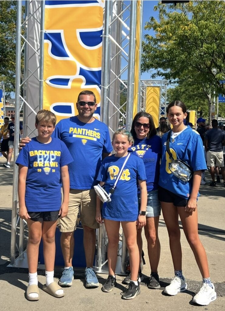 A family of five wear bright blue shirts with yellow Pitt Panthers logos