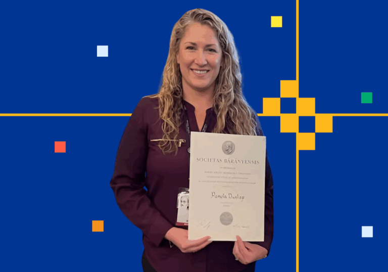 A woman with long blonde curly hair holds a large ornate certificate with her name
