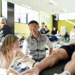 Students in a clinical classroom examine patients while an instructor looks on