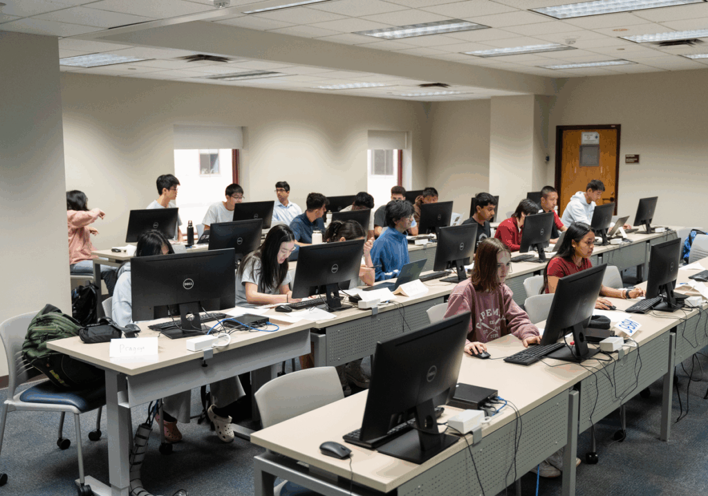 A group of young men and women sitting at rows of desks working on computers.
