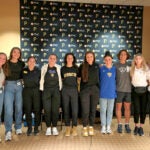A group of men and women standing together in front of a black sign with the Pittsburgh Pirates and PNC Bank logos.