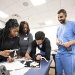 Physician assistant students working together on a medical table to review anatomy.