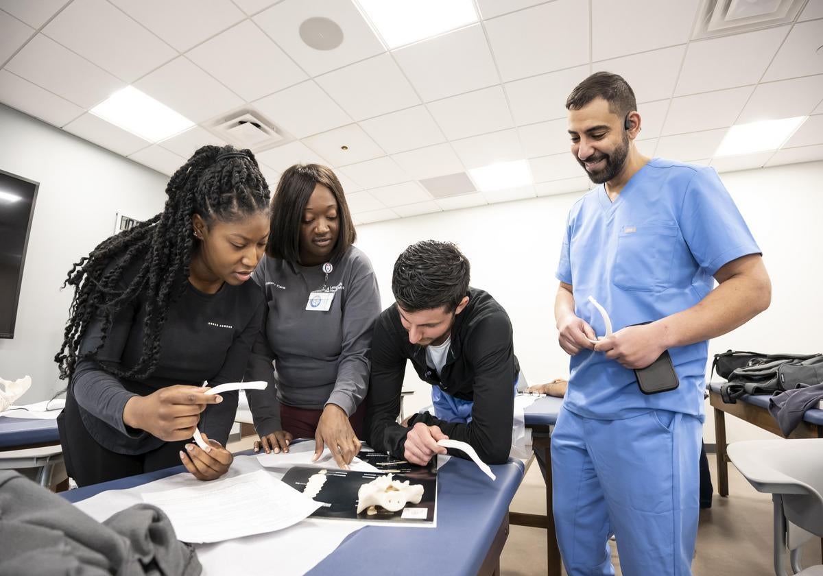 Physician assistant students working together on a medical table to review anatomy.