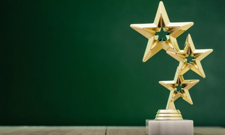 An award sculpture with three gold stars linked on top of each other